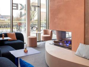 eine Lobby mit einem Kamin, Stühlen und Tischen in der Unterkunft ibis budget Gent Centrum Dampoort in Gent