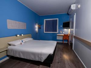 a bedroom with a large bed and a blue wall at ibis budget Iquique in Iquique
