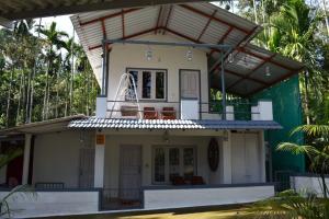 a house with a balcony on top of it at South point homestay in Virajpet