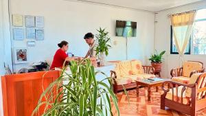 two people sitting at a table in a living room at Hostal Maravilla Amazónica in Iquitos