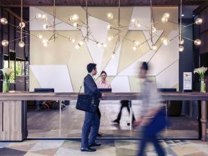 eine Gruppe von Menschen, die an einem Tresen in der Lobby vorbeigehen in der Unterkunft Mercure Jakarta Pantai Indah Kapuk in Jakarta + 44 Fotos