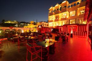 a restaurant with red chairs and tables in front of a building at Shakuntalam Hotels in Udaipur