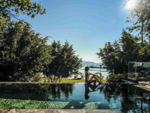 a woman sitting on the edge of a swimming pool at Rixos Premium Göcek - Adult Only in Göcek