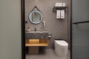 Un baño con lavabo, espejo e inodoro. en Wuxuan Hotel Zoo Branch, en Chongqing