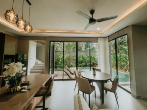 a dining room with a table and chairs and a ceiling fan at Nusari Villa Ubud in Ubud