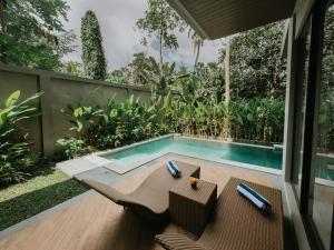 a swimming pool in a backyard with a table and chairs at Nusari Villa Ubud in Ubud
