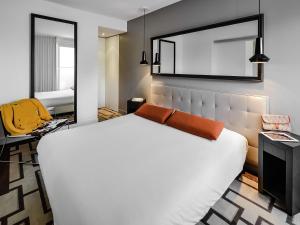 Un dormitorio con una gran cama blanca y un espejo. en Adagio Grenoble Centre, en Grenoble 60 fotos más