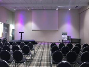 une scène dans une pièce avec des chaises et un podium dans l'établissement Mercure Orléans Portes de Sologne, à Ardon