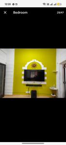 ein Fernseher an einer gelben Wand in einem Wohnzimmer in der Unterkunft Seaface Bldg1BHK Luxe service flat, Mumbai in Mumbai + 16 Fotos