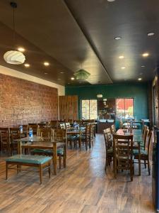 Un restaurante con mesas y sillas de madera y una pared de ladrillos. en Art of greens, en Mahabaleshwar