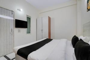a white bedroom with a bed and a tv on the wall at Super Hotel O DLF Phase 1 Metro Station Gurugram in Gurgaon