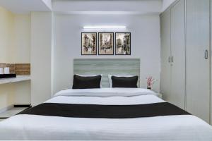 a bedroom with a large white bed with black pillows at Super Hotel O DLF Phase 1 Metro Station Gurugram in Gurgaon