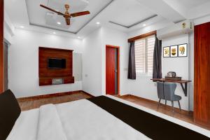 a bedroom with a bed with a ceiling fan and a desk at Super Townhouse Whitefield Railway Station Formerly Kadugudi Whitefield in Bengaluru