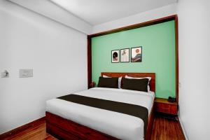 a bedroom with a large bed with a green wall at Super Townhouse Whitefield Railway Station Formerly Kadugudi Whitefield in Bengaluru