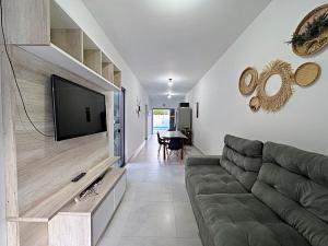 Una sala de estar con un sofá y un televisor de pantalla plana. en Casa aconchegante piscina, en Matinhos