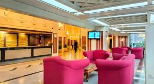 a large room with pink chairs and a television at Danau Toba Hotel International in Medan