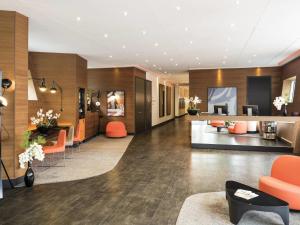 un hall d'hôtel avec des chaises et des tables orange dans l'établissement Adagio Paris 19ème Cité de la Musique, à Paris