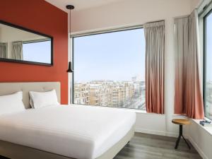 une chambre avec un lit et une grande fenêtre dans l'établissement Adagio Paris 19ème Cité de la Musique, à Paris