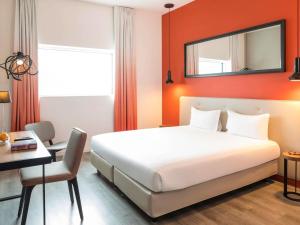 une chambre d'hôtel avec un lit, une table et un bureau dans l'établissement Adagio Paris 19ème Cité de la Musique, à Paris