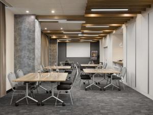 una sala de conferencias con mesas y sillas y una pantalla de proyección en ibis Kyiv Railway Station, en Kiev