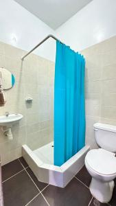 a bathroom with a toilet and a blue shower curtain at Hostal Maravilla Amazónica in Iquitos +25 photos