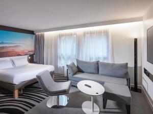 a hotel room with a bed and a couch at Novotel Suites Colmar Centre in Colmar