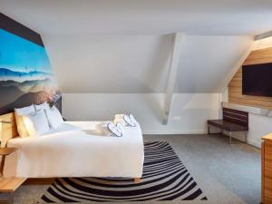 a hotel room with a bed and a flat screen tv at Novotel Suites Colmar Centre in Colmar +109 photos