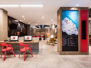 Un vestíbulo de hotel con sillas rojas y un cartel. en ibis Barranquilla, en Barranquilla