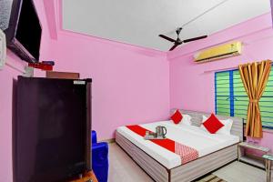 a bedroom with pink walls and a tv and a bed at Hotel O New Orchid Inn in Kolkata
