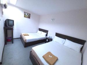 a hotel room with two beds and a television at Hotel Bumimas in Kuantan