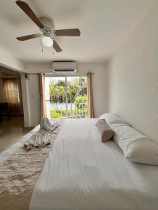 een slaapkamer met een groot wit bed en een plafondventilator bij Villas Cozumel con alberca in Cancun