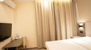 une chambre avec un lit, un bureau et une télévision dans l'établissement 7 Days Inn Tianjin Binhai Passenger Station Huabei Ceramics, à Binhai