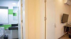 Cette chambre dispose d'une porte blanche et d'une télévision murale. dans l'établissement 7 Days Inn Tianjin Binhai Passenger Station Huabei Ceramics, à Binhai