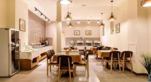 ein Esszimmer mit Tischen und Stühlen und eine Küche in der Unterkunft James Joyce Coffetel·Shenyang North Railway Station Shifu Square in Shenyang