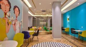 ein Esszimmer mit Tischen und Stühlen und einer blauen Wand in der Unterkunft Magnotel Ningbo Beilun Yintai City Xindalu in Ningbo