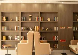 zwei Stühle in einem Raum mit Regalen mit Büchern in der Unterkunft Jtour Inn Wuxi Meiyuan Kaiyuan Temple Metro in Wuxi