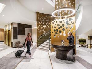 two women walking through a lobby with a suitcase at Novotel Leicester in Leicester
