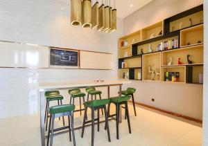 a kitchen with a bar with green stools at City Comfort Inn Suizhou Railway Station in Suizhou