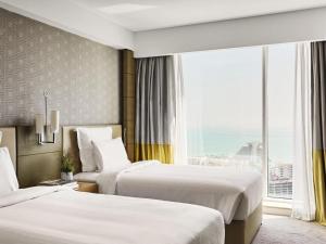 a hotel room with two beds and a large window at Pullman Doha West Bay in Doha