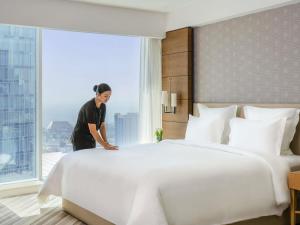 a woman standing next to a large bed in a hotel room at Pullman Doha West Bay in Doha