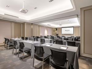 平阴山东平阴美居酒店的一间配有桌椅和屏幕的会议室