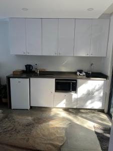 a kitchen with white cabinets and a black microwave at Three Waves in Ballito +1 photo