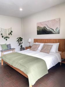 une chambre avec un grand lit avec une couverture verte dans l'établissement Central Nakhon Pathom 2BR Townhouse with AC & Kitchen, à Nakhon Pathom