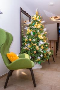 a christmas tree in a room with a green chair at Arena Prestige Rooms in Pula