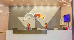 zwei Personen sitzen an einem Tresen in einem Büro in der Unterkunft Borrman Hotel Shaoguan Century East Street Fengcai Building in Shaoguan