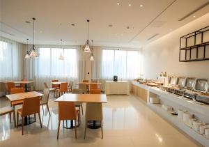 un restaurant avec des tables et des chaises et une cuisine dans l'établissement City Comfort Inn Zhangjiakou Municipal Government High-speed Railway Station North Institute, à Dongyaozi
