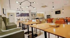 ein Restaurant mit Tischen und Stühlen in einem Raum in der Unterkunft City Comfort Inn Dali High-speed Railway Station Erhai Park in Dali