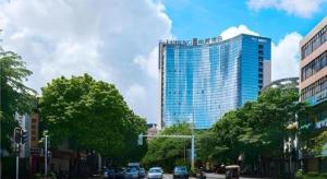 un grand bâtiment en verre dans une rue de la ville avec des voitures dans l'établissement E-Cheng Hotel Yangjiang Baili Plaza, à Yangjiang