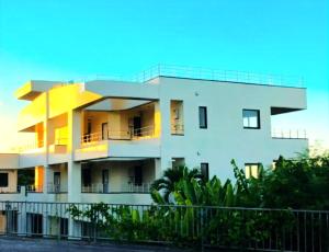a white building with a fence in front of it at Villa resort -悠- in Miyakojima