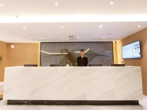 Ein Mann steht hinter einem großen weißen Empfang. in der Unterkunft Green Tree Inn Nanchang Zhongshan Road Bayiguan in Nanchang